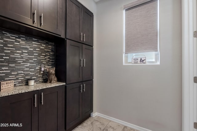 interior space featuring light stone countertops, dark brown cabinets, and backsplash