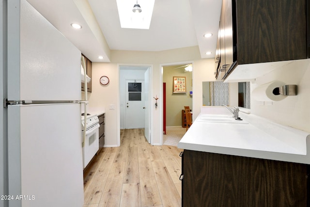 kitchen with a skylight, dark brown cabinetry, sink, light hardwood / wood-style floors, and white appliances