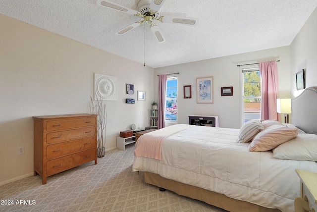 bedroom with ceiling fan, light colored carpet, and a textured ceiling