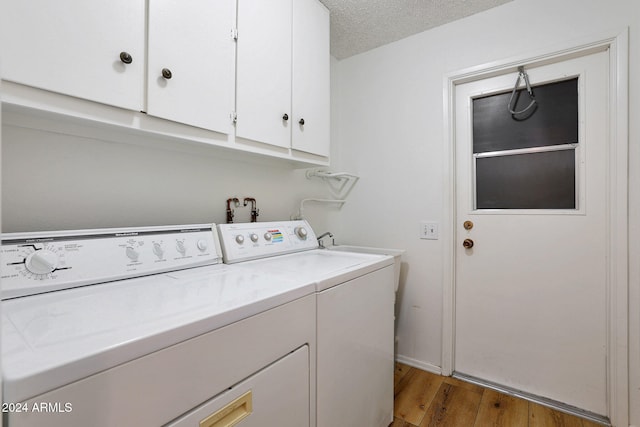 laundry room with light hardwood / wood-style floors, cabinets, independent washer and dryer, and a textured ceiling