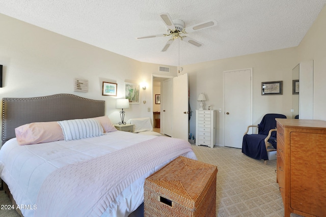 carpeted bedroom featuring ceiling fan and a textured ceiling