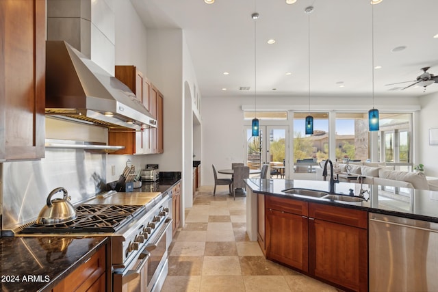 kitchen featuring ceiling fan, sink, wall chimney exhaust hood, pendant lighting, and appliances with stainless steel finishes