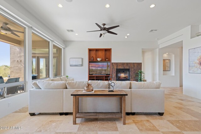 living room with built in shelves, ceiling fan, and a fireplace