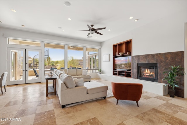 living room featuring french doors, built in features, ceiling fan, and a tiled fireplace