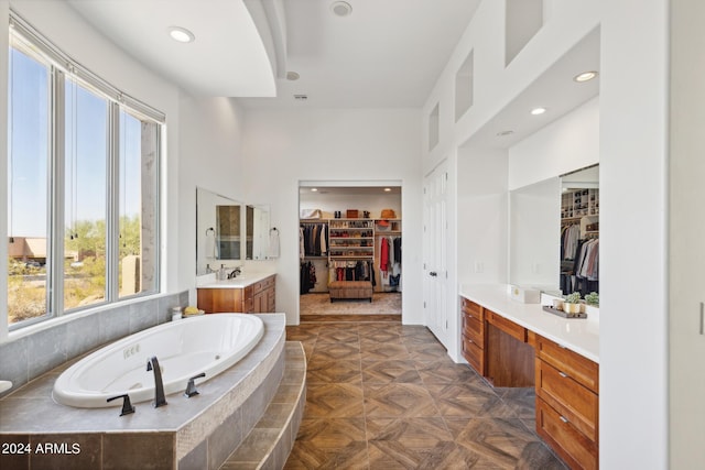 bathroom with tiled bath, a wealth of natural light, vanity, and parquet flooring