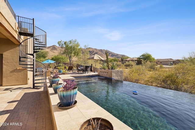 view of swimming pool with pool water feature, a mountain view, and a patio