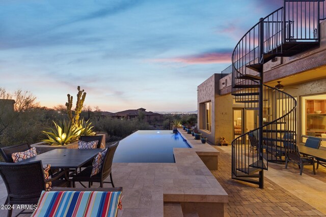 pool at dusk featuring a patio