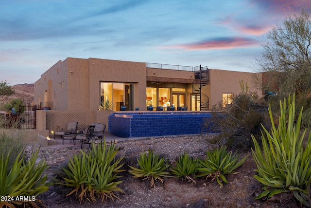 back house at dusk featuring a patio area