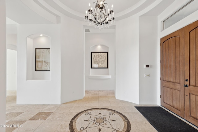 foyer entrance featuring an inviting chandelier and a tray ceiling