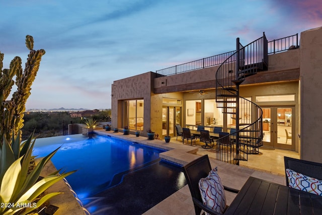 pool at dusk featuring a patio area and french doors