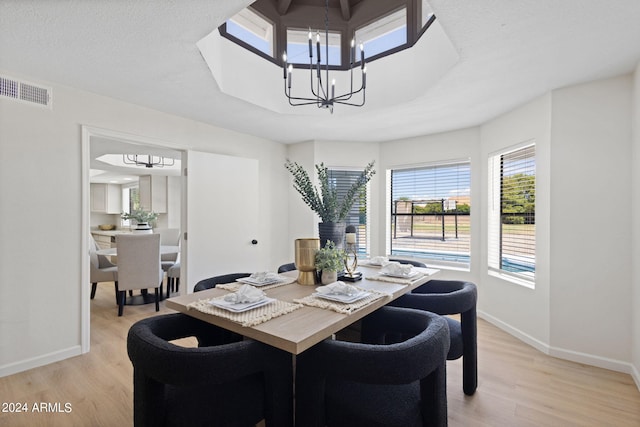 dining area featuring a textured ceiling, light hardwood / wood-style flooring, and a notable chandelier