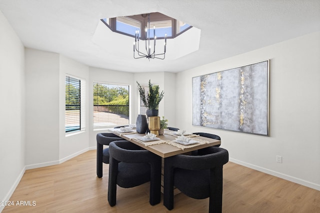 dining area with light wood-type flooring and an inviting chandelier