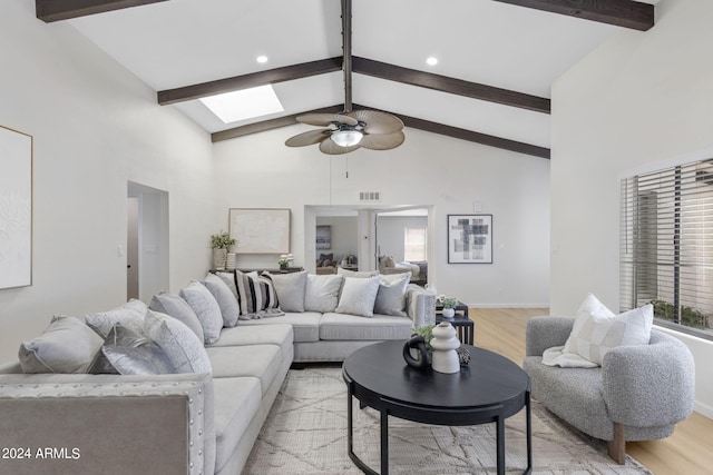 living room with beamed ceiling, a skylight, light hardwood / wood-style flooring, and ceiling fan