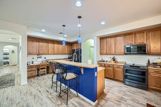 kitchen with a kitchen breakfast bar, an island with sink, appliances with stainless steel finishes, and light hardwood / wood-style flooring