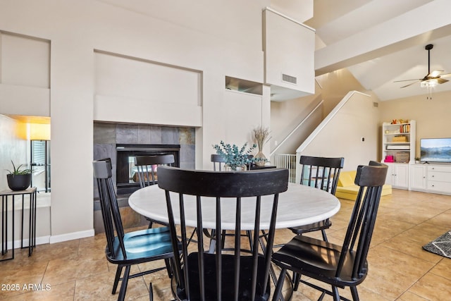 1344 N Brittany Ln, Gilbert, AZ 85233 - dining space featuring ceiling fan, vaulted ceiling, stairs, a tiled fireplace, and light tile patterned flooring