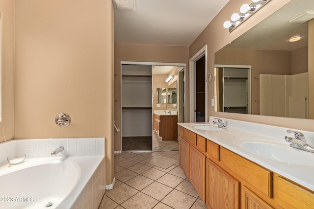 bathroom featuring tile patterned flooring, a relaxing tiled tub, and vanity