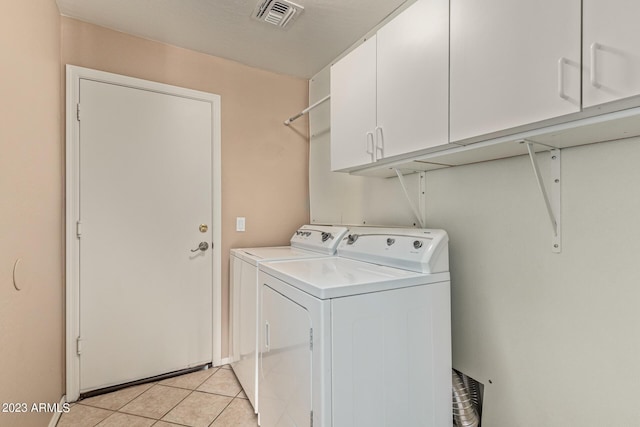 laundry room featuring cabinets, light tile patterned floors, and washing machine and clothes dryer