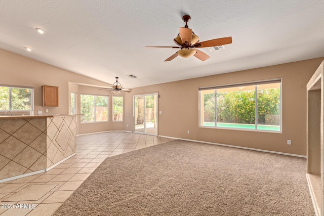 empty room featuring ceiling fan, light tile patterned floors, a textured ceiling, and vaulted ceiling