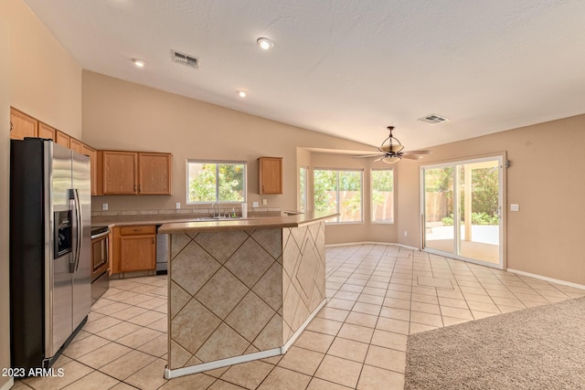 kitchen featuring sink, vaulted ceiling, ceiling fan, light tile patterned floors, and appliances with stainless steel finishes