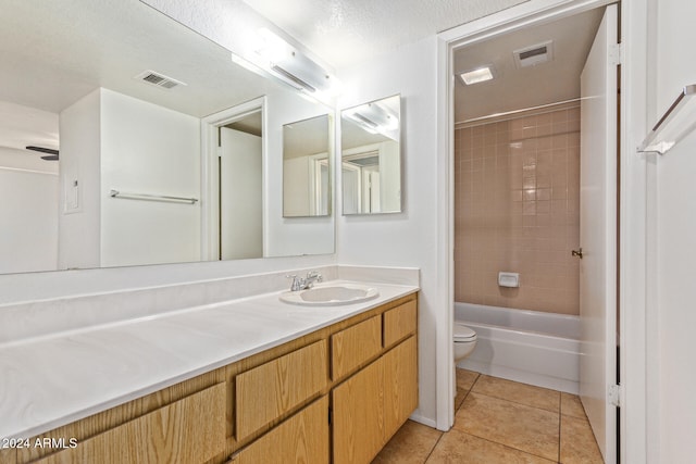 full bathroom featuring toilet, tile patterned flooring, tiled shower / bath combo, vanity, and a textured ceiling