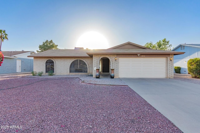 ranch-style home with an attached garage, concrete driveway, and brick siding