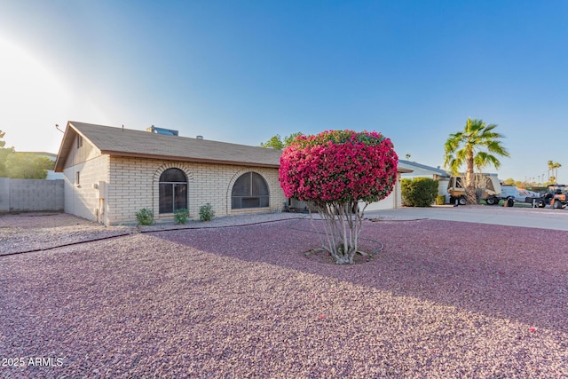 view of front of house featuring a garage, fence, concrete driveway, and brick siding