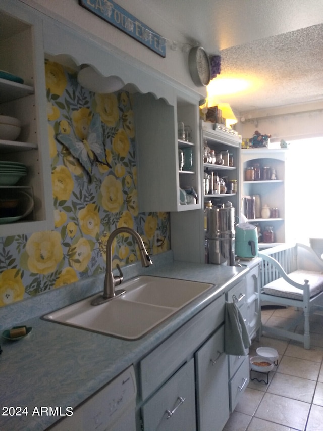 kitchen with gray cabinetry, sink, light tile flooring, and a textured ceiling