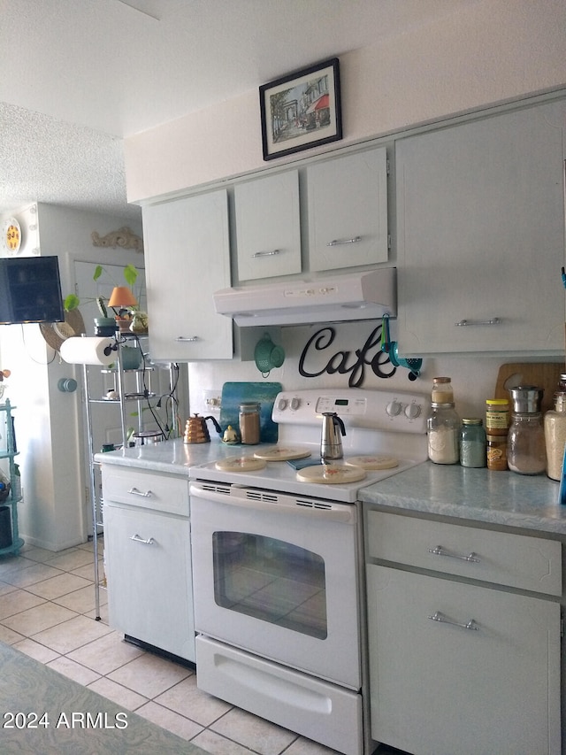 kitchen with wall chimney range hood, electric range, and light tile floors