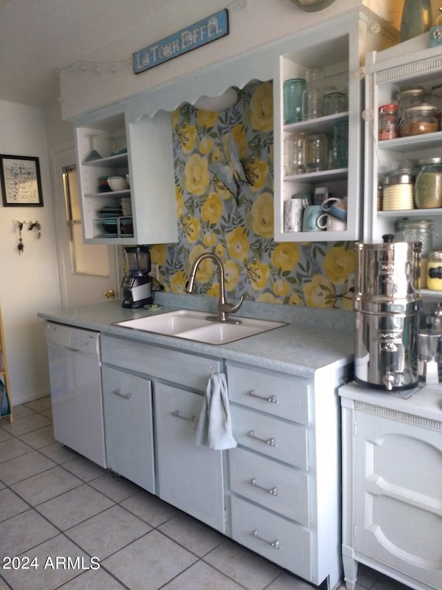 kitchen with white dishwasher, sink, white cabinetry, and light tile patterned flooring