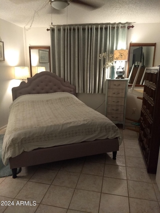 tiled bedroom featuring ceiling fan and a textured ceiling