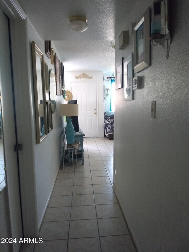 corridor featuring tile patterned flooring and a textured ceiling