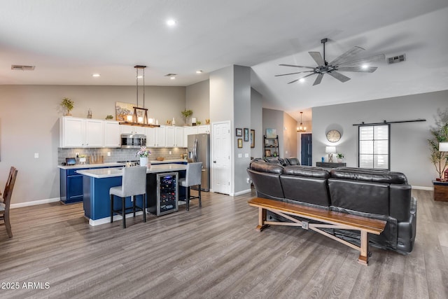 living room with ceiling fan with notable chandelier, wood finished floors, baseboards, and visible vents