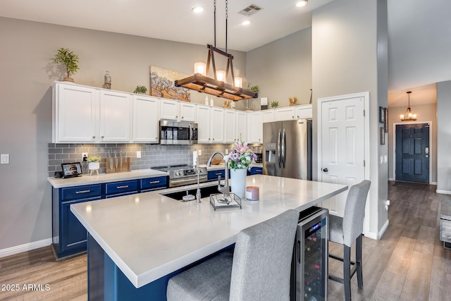 kitchen featuring an inviting chandelier, blue cabinetry, visible vents, appliances with stainless steel finishes, and a sink