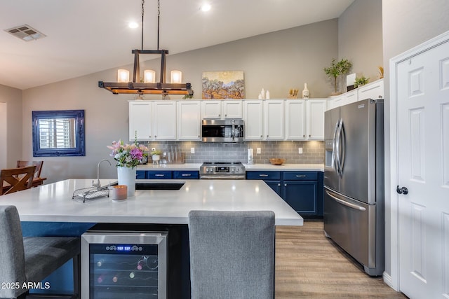 kitchen featuring white cabinetry, visible vents, beverage cooler, stainless steel appliances, and decorative backsplash