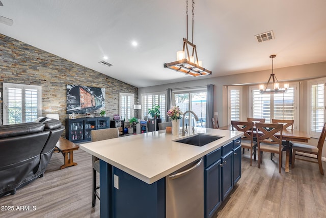 kitchen with blue cabinetry, visible vents, dishwasher, a sink, and open floor plan