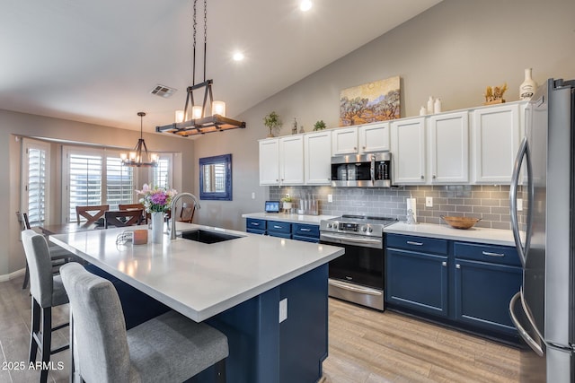 kitchen featuring a notable chandelier, a sink, stainless steel appliances, backsplash, and blue cabinets
