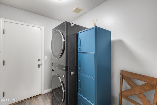 washroom featuring visible vents, laundry area, wood finished floors, and stacked washer and clothes dryer