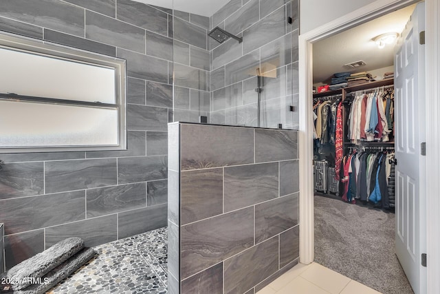 bathroom with a spacious closet, a walk in shower, and tile patterned flooring