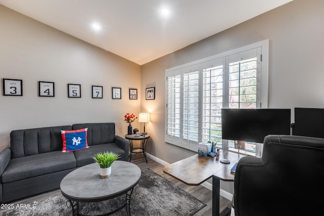 living area with baseboards, vaulted ceiling, and wood finished floors