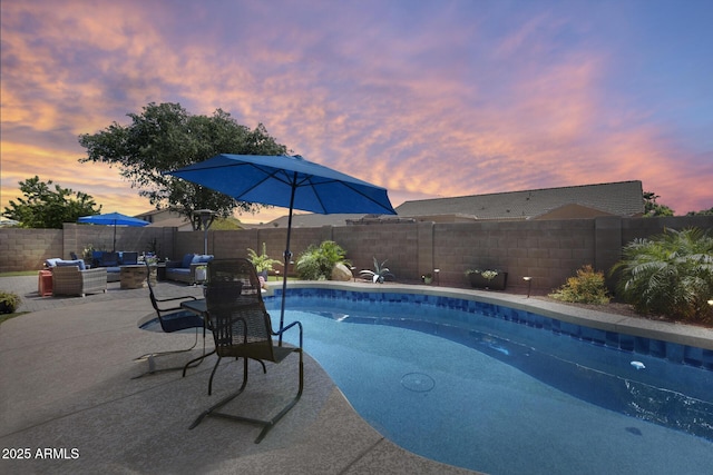 pool at dusk featuring a patio area, a fenced backyard, a fenced in pool, and an outdoor hangout area