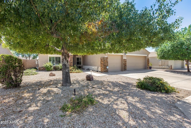 obstructed view of property with stone siding, driveway, stucco siding, and fence
