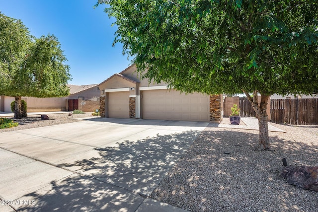 view of property hidden behind natural elements featuring concrete driveway, stone siding, fence, and an attached garage