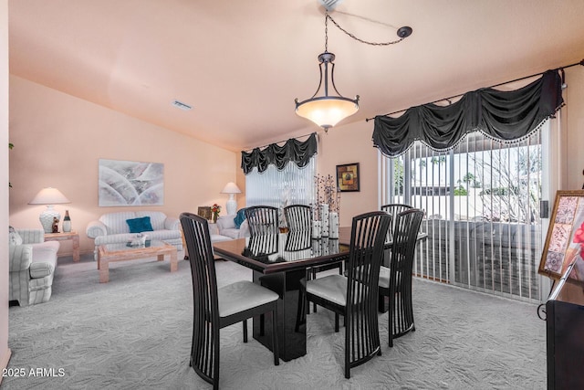 carpeted dining space with lofted ceiling