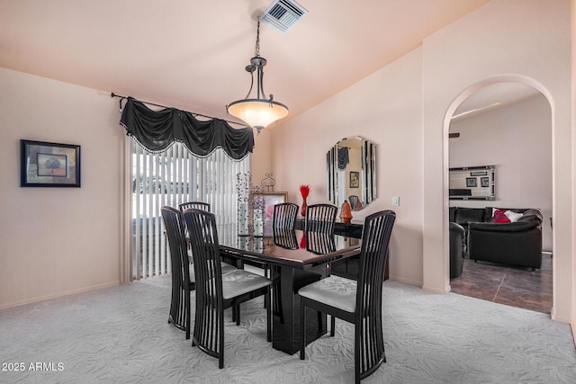 carpeted dining area featuring vaulted ceiling