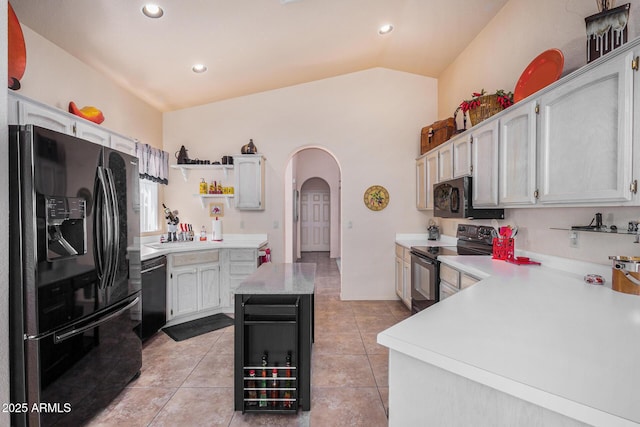 kitchen with black appliances, white cabinets, vaulted ceiling, and light tile patterned floors