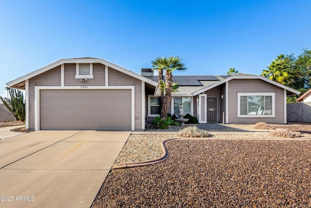 ranch-style home with driveway, solar panels, and a garage