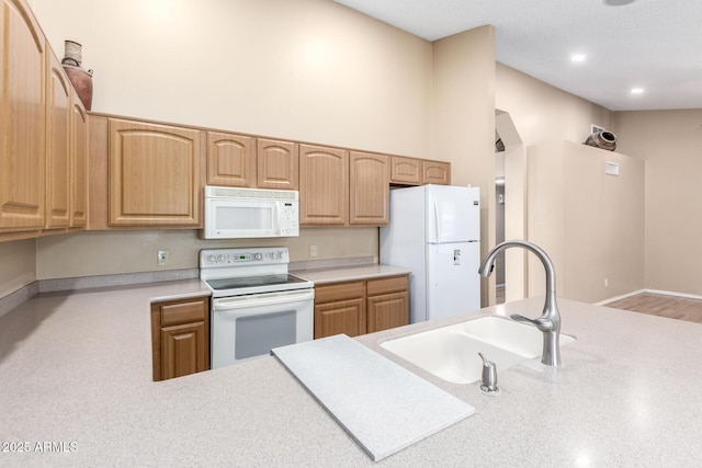 kitchen featuring white appliances, light countertops, baseboards, and a sink