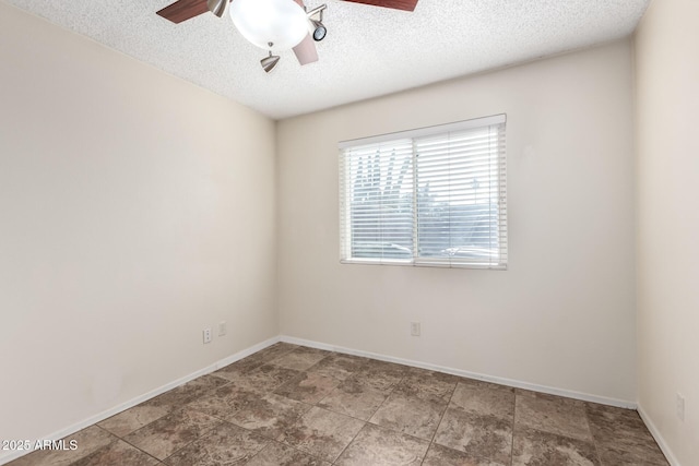 spare room featuring a textured ceiling, ceiling fan, and baseboards