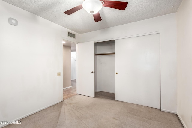 unfurnished bedroom featuring a textured ceiling, visible vents, and light carpet