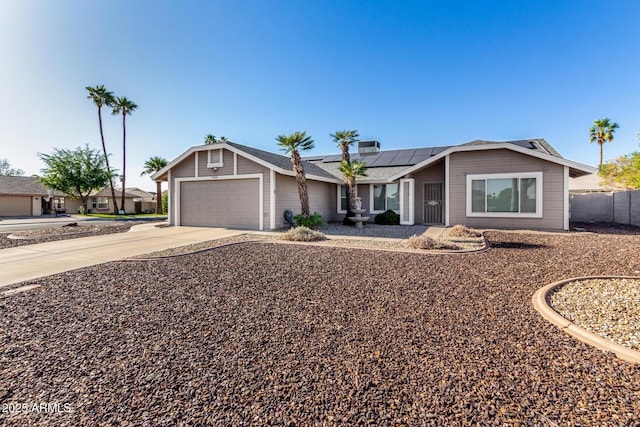 single story home with a garage, fence, solar panels, and driveway
